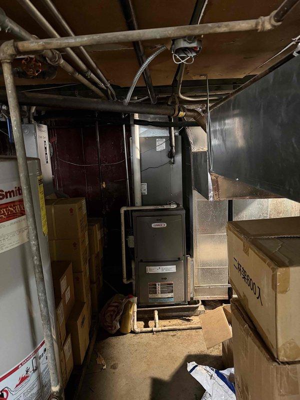 Performed an on-site evaluation for replacement of the existing Lennox gas furnace located in the basement utility area, inspecting the unit, PVC venting, supply plenum and ductwork, gas and electrical connections, and clearances adjacent to the water heater. Documented equipment condition and installation access, noting a narrow, steep stairwell and stored items around the furnace that will need to be cleared prior to removal and installation of the new unit.