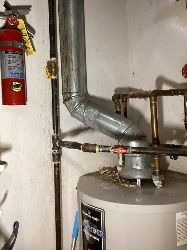 Responded to a reported leak beneath the master bedroom vanity and inspected the sink, faucet, and supply and drain connections, with the water heater closet and its adjacent copper supply lines, gas piping, and flue also assessed. The chrome two-handle faucet and drop-in ceramic basin showed no visible cracks, corrosion, staining, or water damage. Discoloration and residue were noted at several soldered copper joints near the water heater, along with buildup around the flue base, and these areas are recommended for ongoing monitoring.