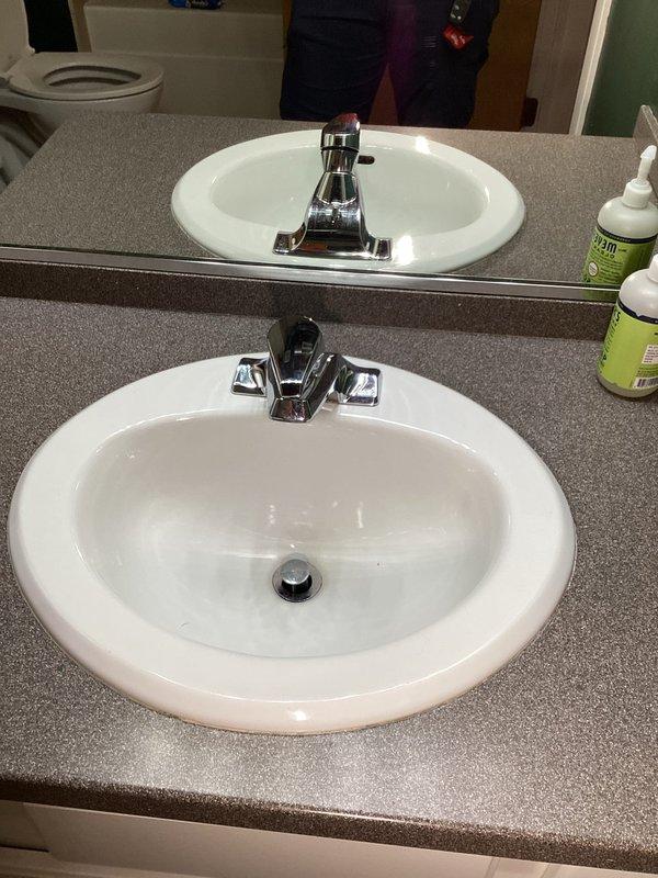 Responded to a reported leak beneath the master bedroom vanity and inspected the sink, faucet, and supply and drain connections, with the water heater closet and its adjacent copper supply lines, gas piping, and flue also assessed. The chrome two-handle faucet and drop-in ceramic basin showed no visible cracks, corrosion, staining, or water damage. Discoloration and residue were noted at several soldered copper joints near the water heater, along with buildup around the flue base, and these areas are recommended for ongoing monitoring.