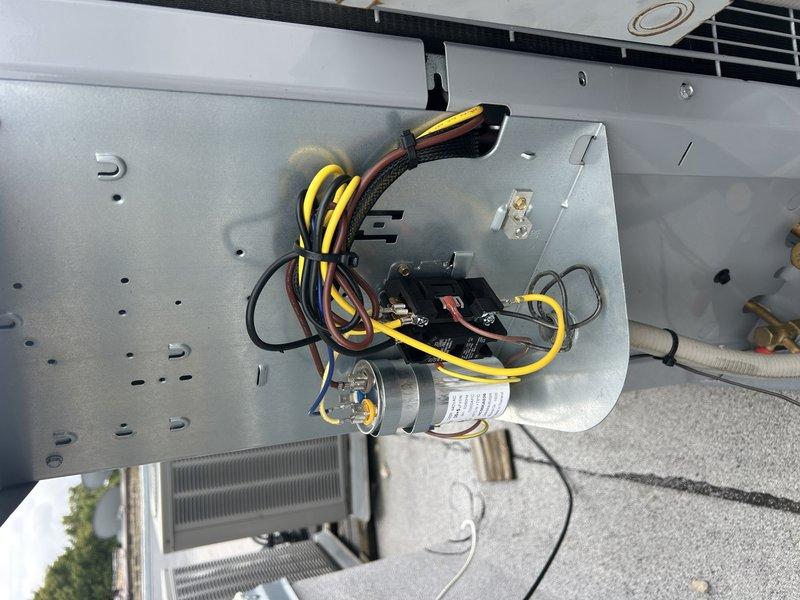 Responded to a warranty call for an intermittent no-cooling condition on a recently replaced AC system. Inspected the outdoor condensing unit's electrical disconnect and control section, finding dust accumulation and corrosion on the disconnect enclosure and conduit entries, with the contactor, run capacitor, and wiring harness showing no visible damage or failure. The system was operating normally following a customer breaker reset, and the electrical connections should be monitored for recurrence of a tripped breaker.