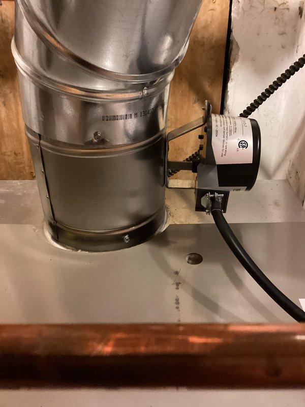 Returned to replace a defective flue damper actuator motor on the recently installed boiler under manufacturer warranty. Removed the failed motor from its mounting bracket, installed the new warranty motor, and reconnected the wiring, then verified secure mounting and proper damper blade operation with no visible damage to the flue or connected components.