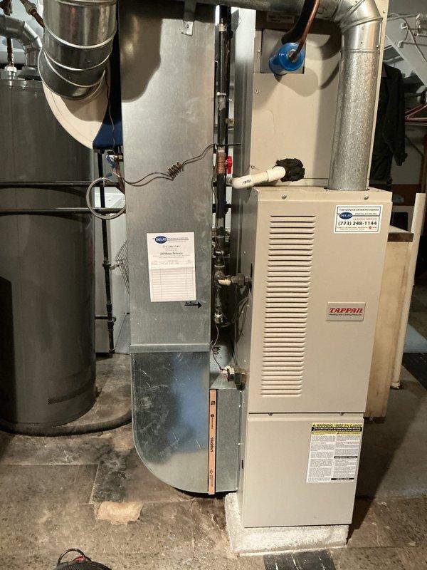 Performed annual maintenance on a natural gas upright furnace, including visual inspection of the cabinet, plenum, flue venting, and gas piping, with no frost, ice, or significant corrosion observed. Verified system operation and checked supply air temperature with a digital pocket thermometer, which measured approximately 80°F. Noted accumulated dust and debris around the furnace base.