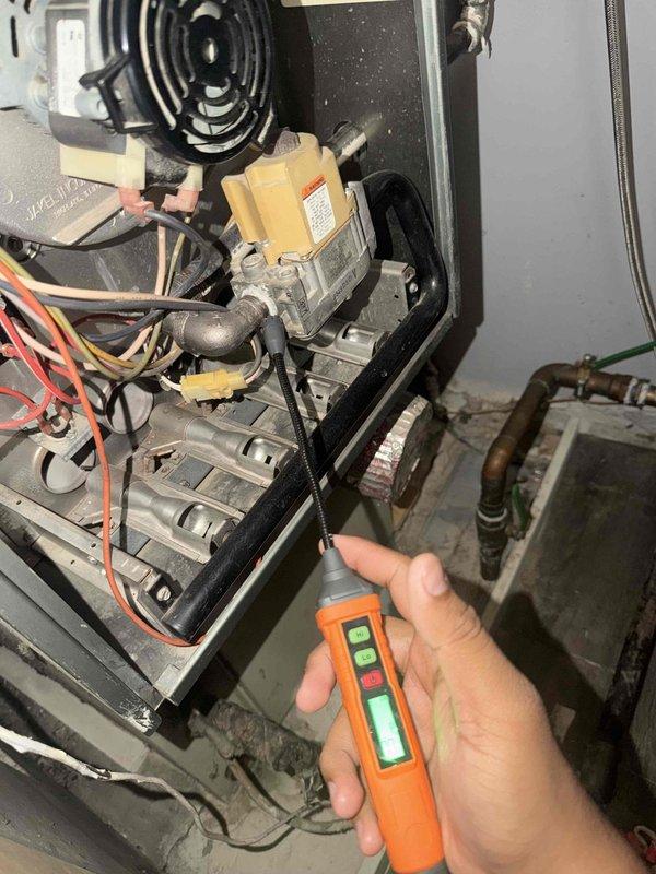 Performed a maintenance inspection and tune-up on the gas furnace, including removal of the access panel to inspect the burner assembly, gas valve, and associated wiring. Checked gas connections and fittings for leaks using an electronic combustible gas detector, and inspected the refrigerant and condensate lines for insulation condition and corrosion. Noted dust and debris buildup around the base of the unit and tarnishing on the copper line set.