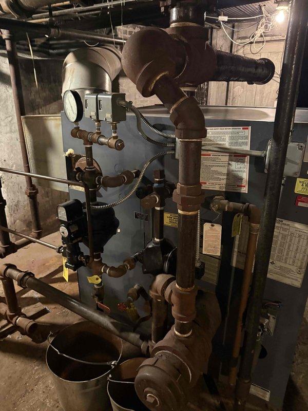 Performed on-site evaluation of a 30+ year-old steam boiler system in a condominium mechanical room for full replacement. Documented the existing boiler, controls, gauges, and heavily oxidized iron piping and fittings, and took clearance measurements of the mechanical space to support equipment sizing and replacement planning.