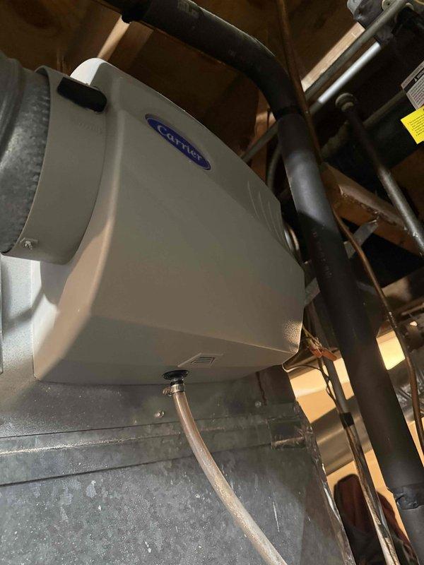 Performed an on-site evaluation and prepared a quote for full system replacement of an approximately 13-year-old HVAC system. The outdoor condenser unit, set on a concrete pad, was inspected and found to have heavy leaf and debris accumulation around its base and conduits. The attic-mounted Carrier whole-house humidifier, with its duct connection and drain line, was inspected and found clean and intact. Documented the equipment with photos to support the replacement proposal.