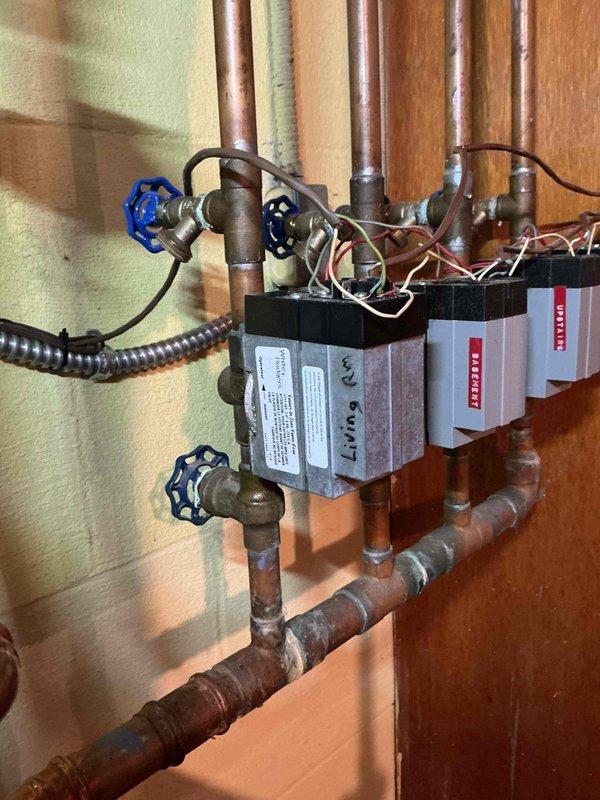 Performed diagnostic inspection on recently installed boiler system to address customer concern about a leaking valve. Identified issue with one of the zone valve assemblies in the hydronic heating system. Photos documented the multiple zone control setup with copper supply/return lines and electronic control boxes for the various heating zones.