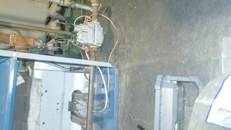 Inspected aging boiler system in utility room showing significant oxidation and corrosion on copper piping and connections. Noted temperature sensor appears to be properly installed but connected to aging infrastructure. Recommend replacement of corroded components and comprehensive evaluation of the boiler system to prevent future failures.