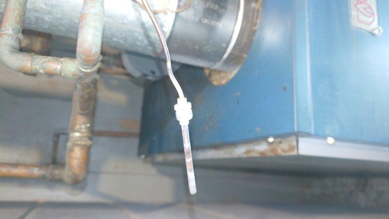 Inspected aging boiler system in utility room showing significant oxidation and corrosion on copper piping and connections. Noted temperature sensor appears to be properly installed but connected to aging infrastructure. Recommend replacement of corroded components and comprehensive evaluation of the boiler system to prevent future failures.