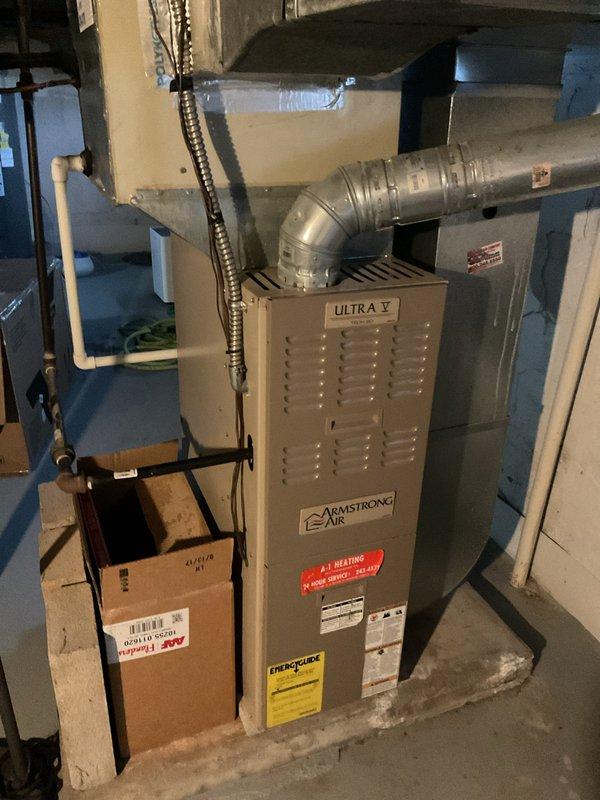 Completed estimate for replacement of an Armstrong Air "Ultra V" furnace currently installed in basement utility area. Existing unit shows normal wear with complete ductwork system including metal elbow connections and proper ventilation. Proposal includes removal of current equipment and installation of new compatible furnace with all necessary connections to existing ductwork, gas, and condensate drain systems.
