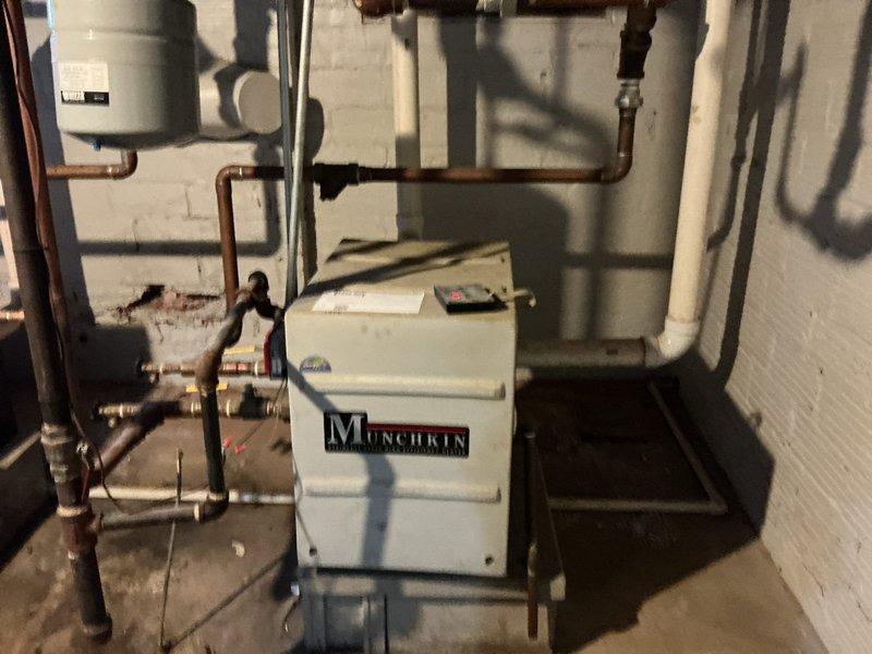 Performed inspection of Munchkin boiler system in basement utility room. Examined copper piping network, connections, valves, and expansion tank for proper installation and functionality. System appears operational with no visible leaks or immediate concerns noted.
