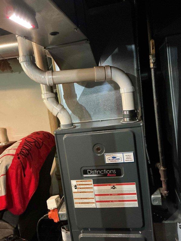 Responded to customer concern regarding unusual noise from Amana Distinctions furnace. Performed diagnostic inspection of the system, focusing on the condensate drainage assembly with particular attention to the drain trap and associated PVC piping. Tightened loose hose clamps on the condensate line that were causing vibration noise during operation. System now functioning properly with no unusual sounds.