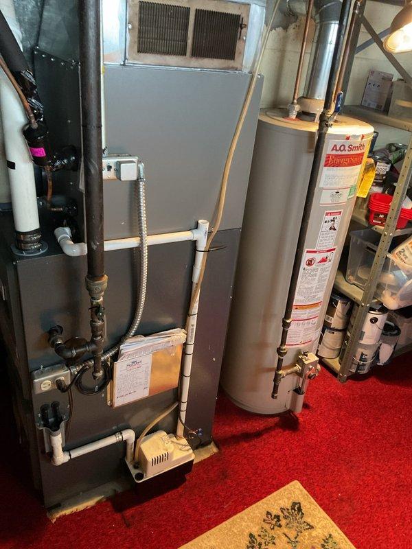 Conducted a site assessment for furnace replacement in client's utility room. Existing setup includes an aging furnace unit with standard vent connections and a separate A.O. Smith water heater. Inspection of the PVC venting system and surrounding structural elements indicates standard replacement procedures can be followed with no apparent complications.