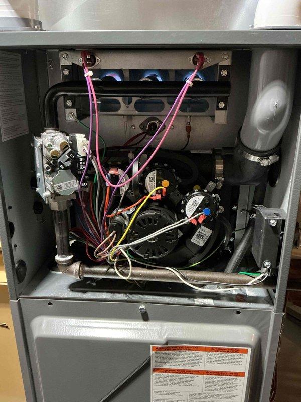 Responded to no-heat call for 3-year-old furnace with MVP warranty valid until 2025. Upon inspection of the interior components, found the furnace not operating due to a faulty blower motor, evidenced by the disconnected wiring. Replaced the defective motor assembly, reconnected all electrical components (pink, yellow, white, and green wires), and verified proper gas valve operation. System now functioning correctly with normal heating cycle restored.