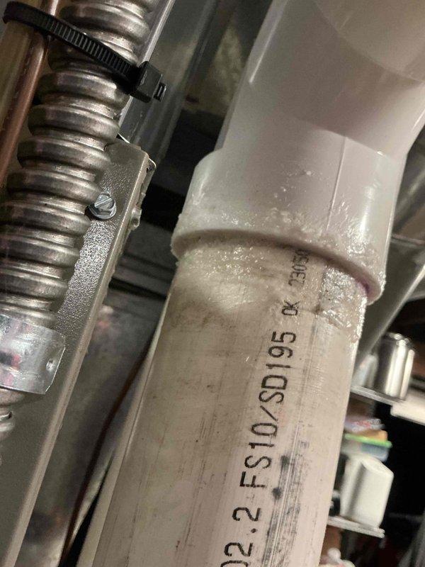 Responded to service call for 2-year-old furnace with reported leak. Inspection revealed condensate drain line issue with compromised PVC pipe connection (FS10-SD195). Resealed joint with PVC primer/cement and verified proper drainage. System now operating normally with no leaks detected.