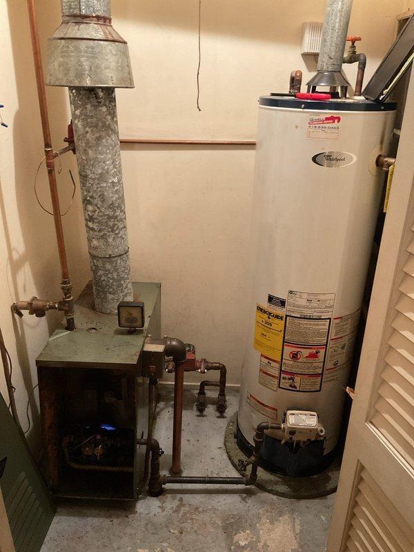 Performed comprehensive assessment of existing boiler system for replacement. Documented current installation consisting of Whirlpool water heater with circulation pump and associated copper piping network. Evaluated adjacent furnace/heating unit with connected galvanized ductwork to ensure proper integration with proposed new boiler system.