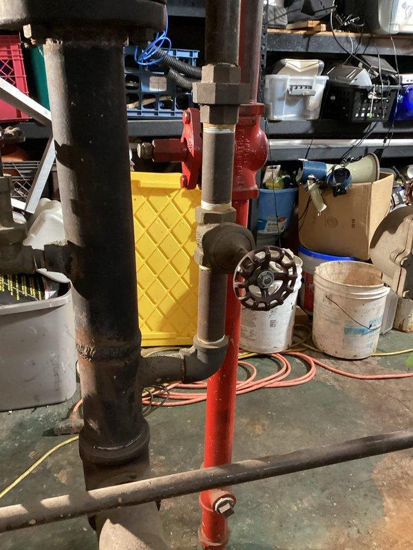 Initiated removal of existing steam gas boiler system as scheduled. Documented existing plumbing infrastructure including main valve assembly and pipe connections. Identified IOWA model E 40-2487 pump/valve component with protective drip tray for assessment during replacement process.