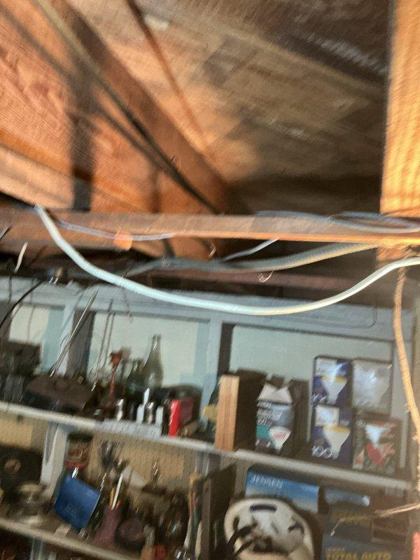 Performed inspection of hot water tank and identified severely corroded exhaust vent. Documented condition with photos showing the deteriorated ventilation system in relation to surrounding structural elements and plumbing infrastructure. Recommended replacement of rotted exhaust components to prevent potential carbon monoxide hazards.