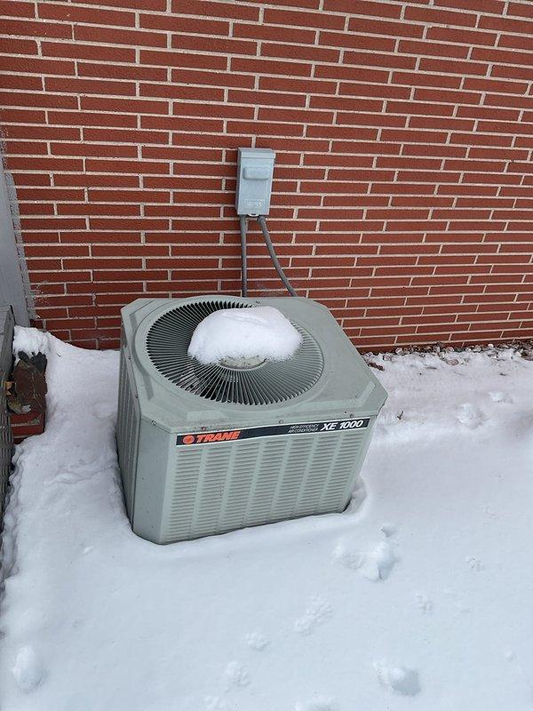 Conducted final quote assessment for HVAC system replacement. Current setup includes an aging Trane XE 1200 outdoor unit showing signs of winter exposure and snow accumulation, paired with an indoor furnace installed in utility closet with standard PVC venting. Replacement recommendation prepared based on visual inspection of both components.