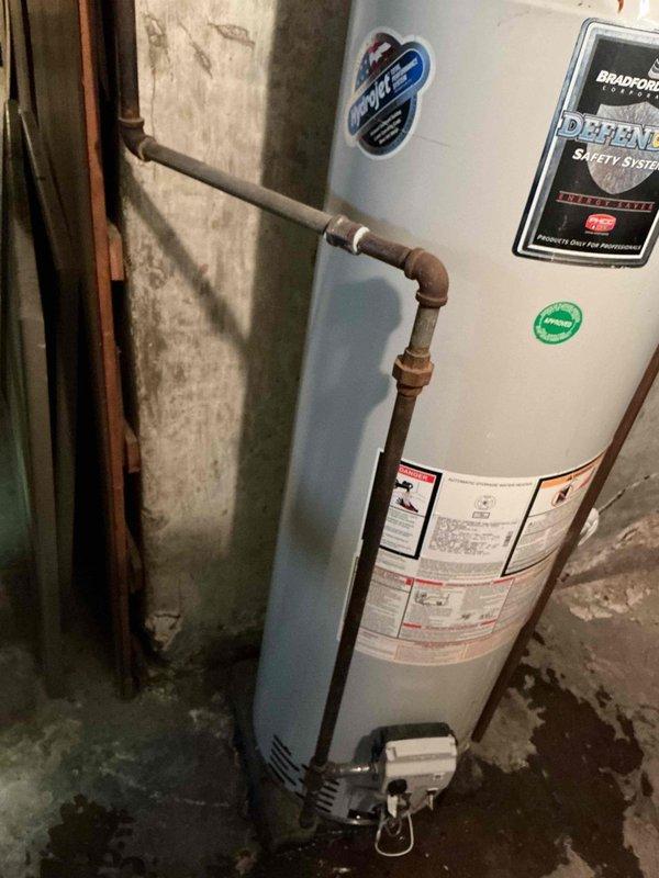 Diagnosed and repaired leaking Bradford White tanked water heater in 120-year-old residence. Identified water pooling at base of unit and moisture staining on concrete floor, indicating tank failure. Replaced aging water heater with proper connections to existing copper plumbing system.