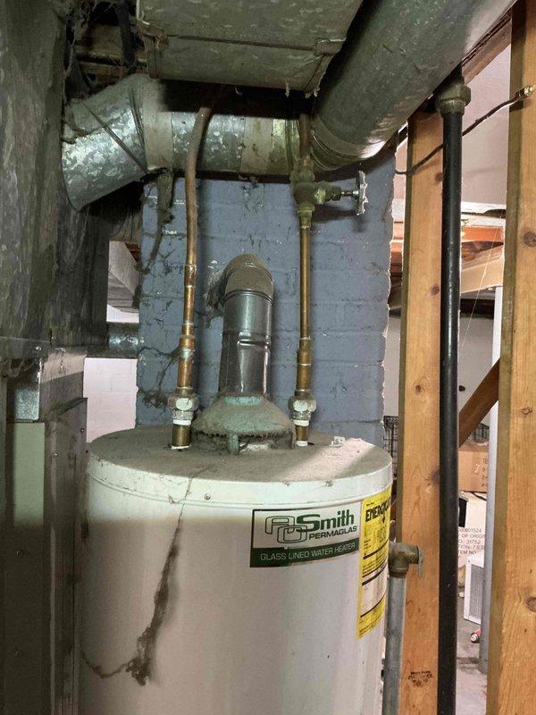 Performed diagnostic assessment on an aging A.O. Smith tank water heater showing significant corrosion and mineral buildup around top connection points. Identified and addressed issues with copper and brass pipe connections, focusing on the deteriorated areas at the tank's top where mineral deposits had accumulated. Restored proper functionality to the system, ensuring safe and efficient operation.