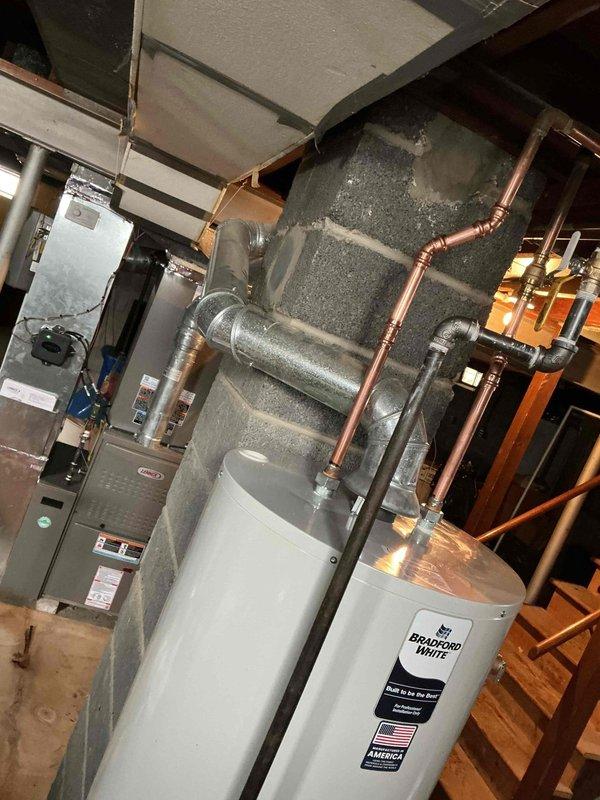 Responded to emergency service call for leaking Bradford White hot water tank in 74-year-old home. Upon inspection in basement utility area, identified tank failure requiring complete replacement. Successfully installed new water heater, connected existing copper supply lines, and verified proper operation with no leaks.