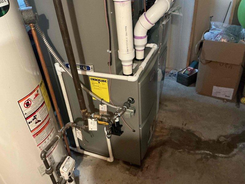 Diagnosed 1-year-old natural gas furnace with water leakage. Inspection revealed condensate drainage issues with visible water staining at the base of the unit. Cleared blocked condensate line and verified proper drainage function to resolve the leak.