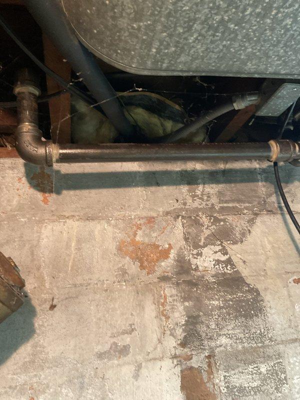 Conducted comprehensive inspection of aging furnace system in basement utility area with visible wear on copper piping and associated ductwork. Observed significant deterioration on horizontal copper lines showing discoloration and potential water damage to surrounding concrete floor. Recommend complete system replacement due to age-related component failure and inefficient operation of current unit.