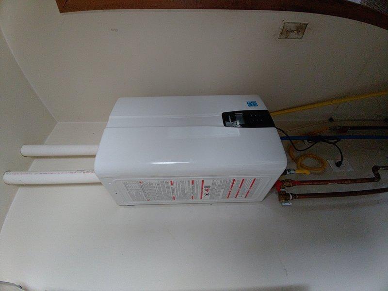 Responded to service call for a 5-year-old tankless water heater displaying an orange blinking light with exhaust issue warning. Upon inspection of the wall-mounted unit, identified fault in the exhaust ventilation system. Performed thorough cleaning of the PVC vent pipes and verified proper connection of gas line and copper water lines. Reset system and confirmed return to normal operation with green status light.