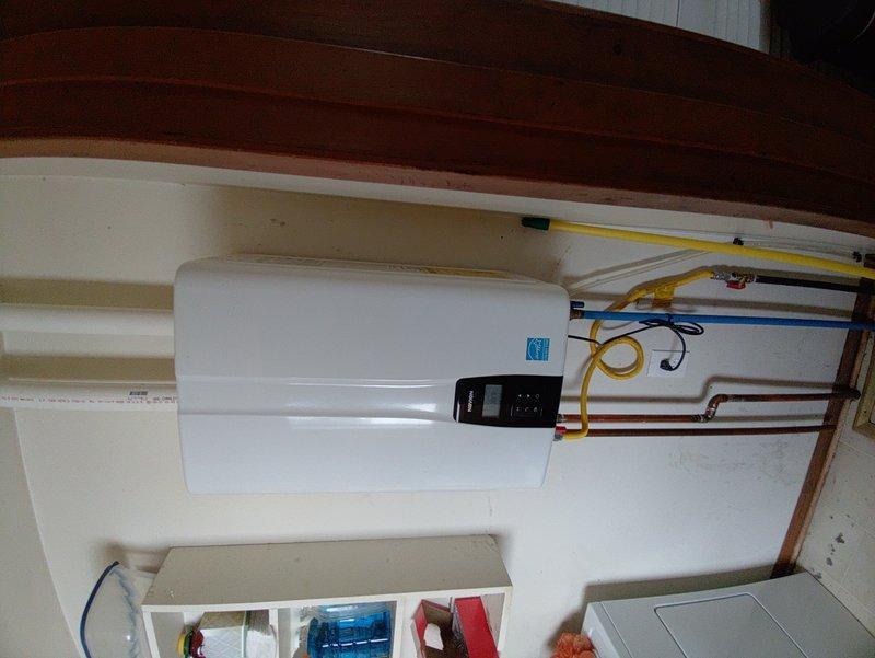 Responded to service call for a 5-year-old tankless water heater displaying an orange blinking light with exhaust issue warning. Upon inspection of the wall-mounted unit, identified fault in the exhaust ventilation system. Performed thorough cleaning of the PVC vent pipes and verified proper connection of gas line and copper water lines. Reset system and confirmed return to normal operation with green status light.