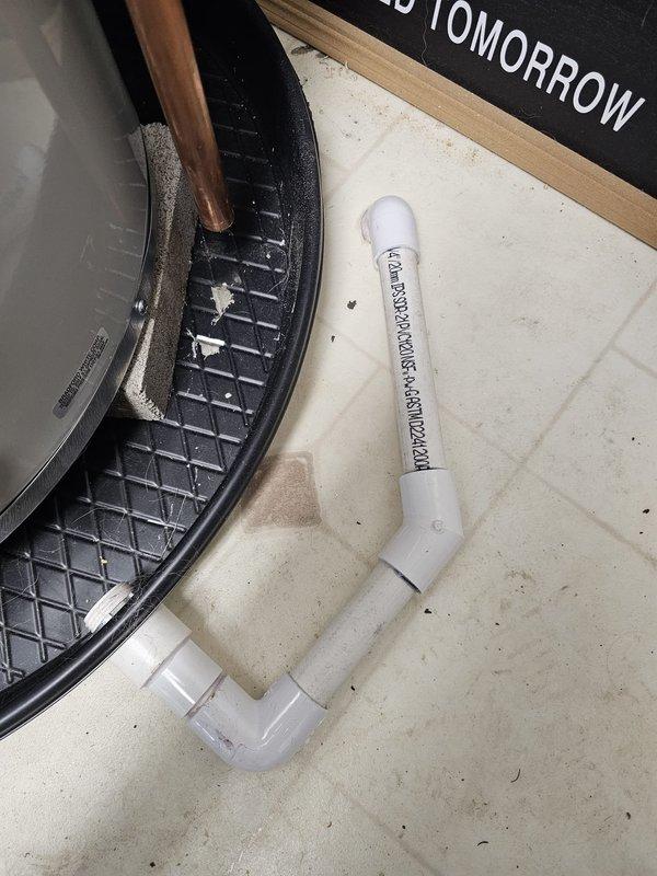 Completed install call back service by drilling drainage hole through floor for water heater drain pan and installed S40 room sensor for thermostat system. Documented existing water damage at fixture-wall junction that requires attention.