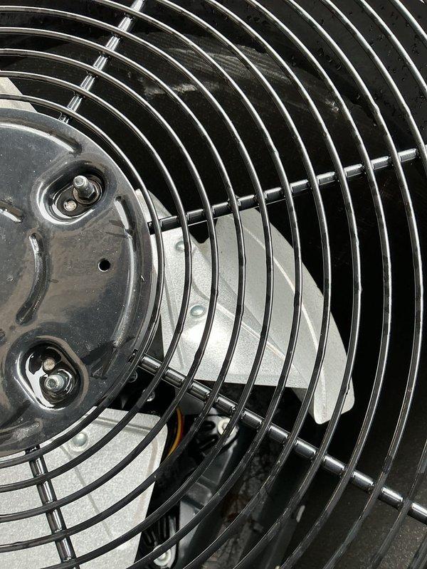 Completed diagnostic inspection on a 2-year-old air conditioning system with reported condenser damage. Visual examination revealed the condenser fan assembly and protective housing were intact with some minor water staining and residue buildup. Performed necessary repairs to restore proper system operation and documented condition with photographs for service record.