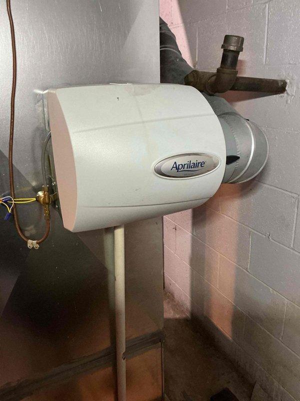 Performed scheduled heating maintenance service. Inspected Aprilaire 500 Series whole-home humidifier, verifying proper mounting to ductwork, water supply connection integrity, and overall operational condition. Unit appears functional with normal wear; documented installation with photos showing humidifier mounted to ductwork with connected water supply and drain lines.