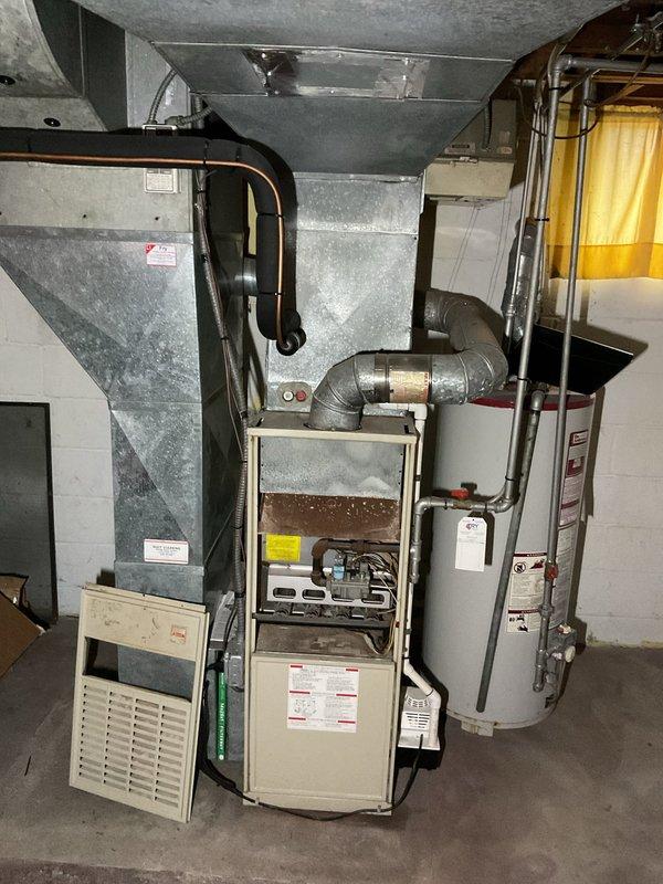 Conducted comprehensive assessment of existing HVAC system in basement utility area, including furnace unit with connected ductwork, air handler, and adjacent water heater system. Provided detailed replacement estimate for upgrading the aging furnace system, noting the current installation's configuration with metal plenum, 90-degree ductwork bends, and integration with existing water heating infrastructure.