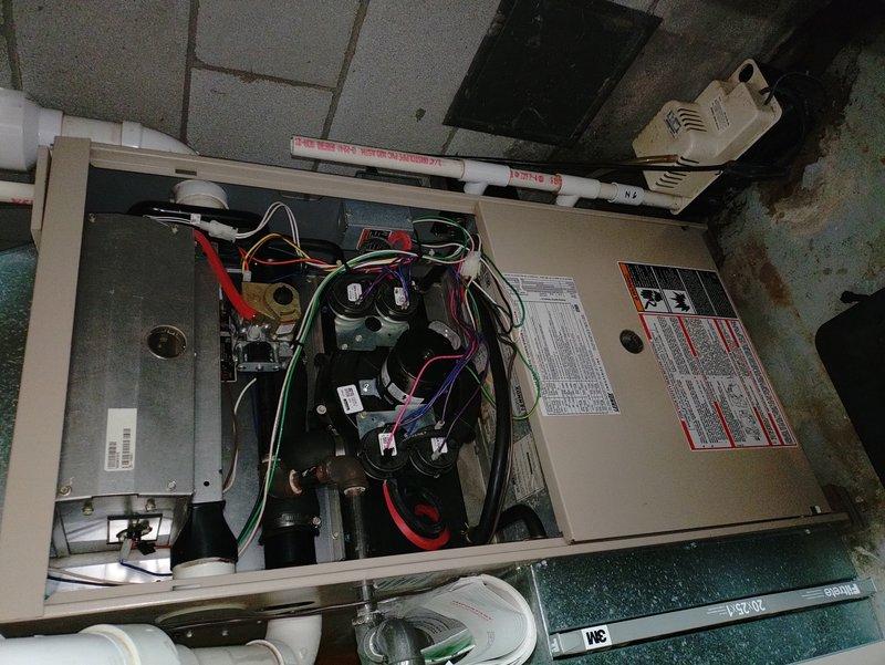 Performed scheduled maintenance inspection on residential furnace system. Identified water leak underneath the unit with visible staining on the floor. Visual inspection of internal components completed with front panel removed, showing proper wiring connections but evidence of water intrusion requiring further attention.