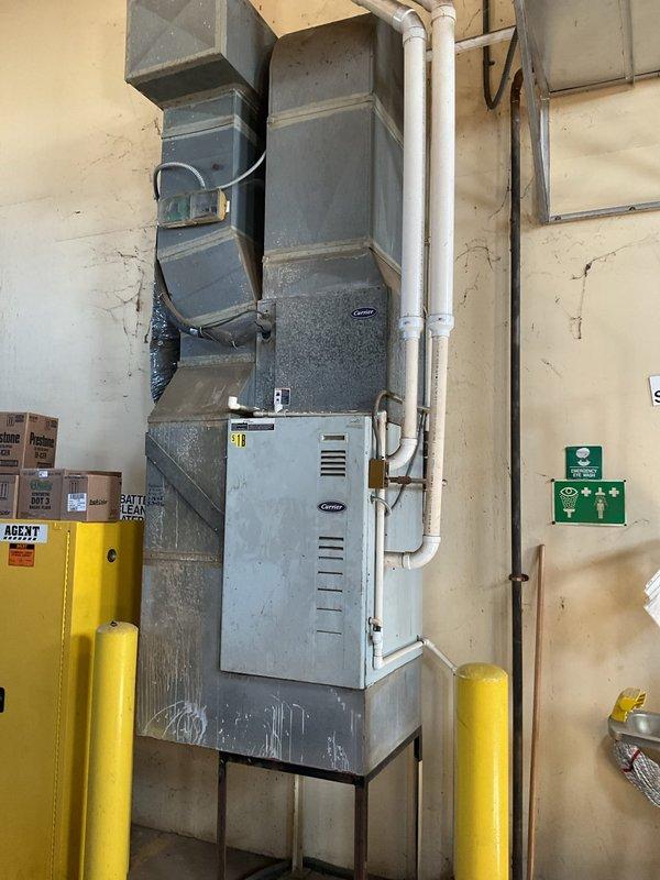 Conducted site assessment for furnace and heat exchanger replacement, documenting the existing outdoor AC condenser unit with proper electrical connections and disconnect switch. Evaluated the indoor Carrier HVAC system showing signs of aging with visible wall cracks nearby, noting the current ductwork configuration and PVC drainage/ventilation pipes that would need to be integrated with any new installation.