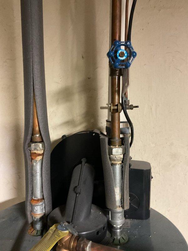 Conducted comprehensive assessment of existing water heater system and associated plumbing components. Identified aging copper supply lines with visible mineral deposits at connection points and documented current valve configuration including functional blue shutoff valve. Prepared detailed quote for replacement unit with financing options, documenting existing installation constraints with photographic evidence of utility area layout and current piping arrangement.
