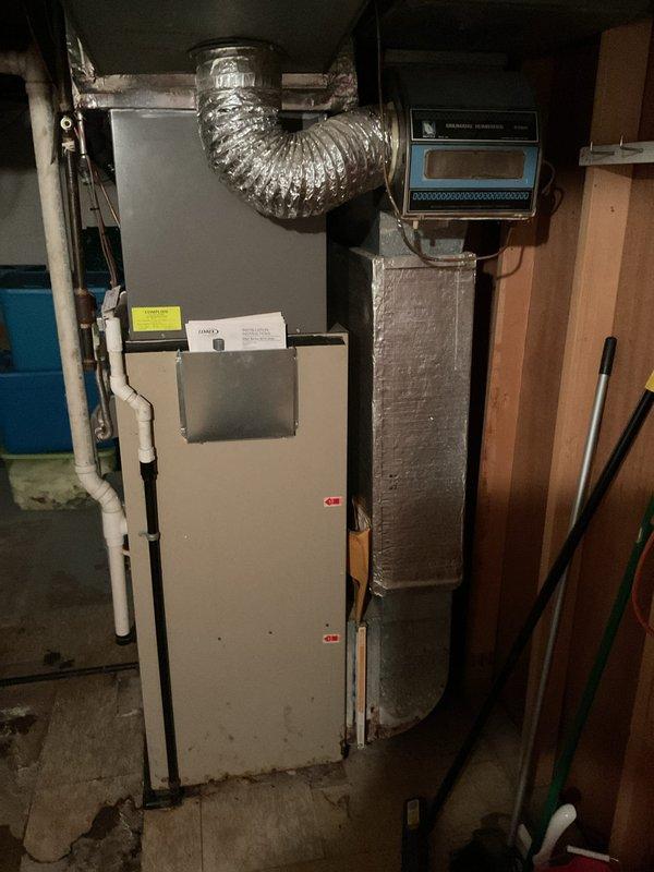 Inspected non-operational furnace of indeterminate age located in basement utility area. Visual examination revealed an aging beige/tan unit installed against cinder block wall with visible moisture staining around base. Recommended complete system replacement due to age-related component failure and signs of water damage that could impact reliable operation.