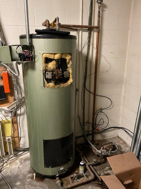 Conducted assessment of commercial water heater requiring replacement. Inspection revealed significant deterioration of internal insulation with visible discoloration around control area. Unit shows signs of wear with damaged yellow insulation material exposed through access panel, indicating potential safety and efficiency concerns that warrant full replacement rather than repair.
