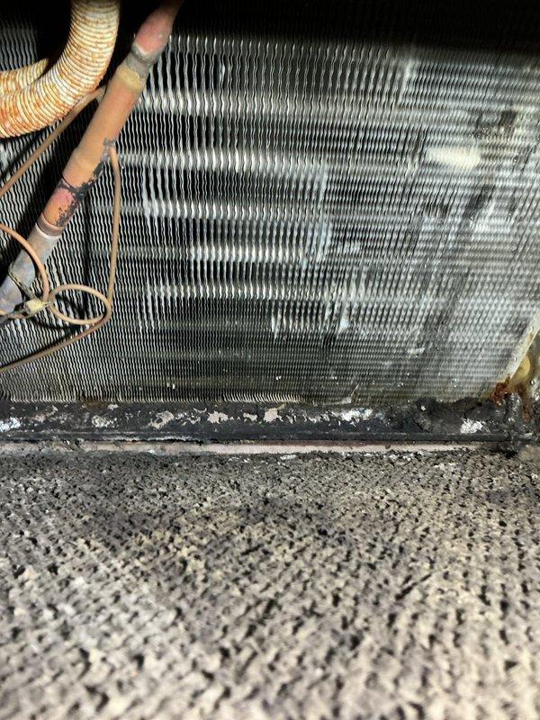 Responded to service call for leaking and frozen furnace coils. Inspection revealed significant dust accumulation, possible corrosion, and deterioration on evaporator coil assembly with orange discoloration on upper portions. Observed copper refrigerant lines with compromised insulation and evidence of moisture issues causing freezing.