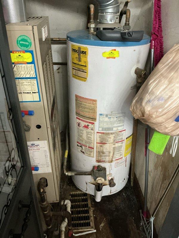 Responded to service call for a 10+ year old natural gas water heater exhibiting operational issues. Upon inspection, observed an aging tank-style water heater with copper supply lines and proper venting connections to the adjacent HVAC system. Diagnostic assessment revealed end-of-life conditions requiring replacement recommendation due to age and declining performance.