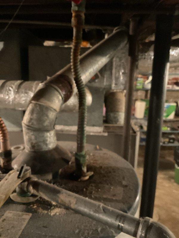 Provided estimate for replacement of 50-gallon water heater in basement utility area. Inspection revealed aging unit with visible corrosion on galvanized elbow joint and mineral deposits around connections. Noted existing copper supply lines with valve and evaluated current installation configuration for proper replacement.
