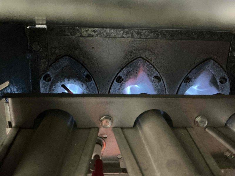Responded to no-heat call for 10-year-old residential furnace that was shutting off immediately after ignition attempt. Diagnostic inspection revealed significant sooting and flame impingement on the heat exchanger tubes, causing the high-limit switch to trip. Performed thorough cleaning of burner assembly, removed debris from heat exchanger surfaces, and adjusted gas pressure to achieve proper flame characteristics with even blue flames across all three burners.