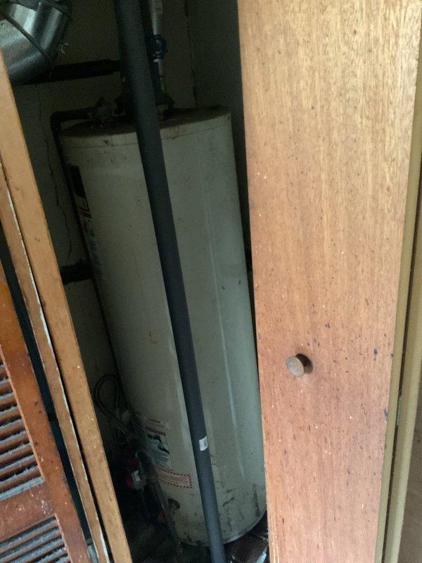 Assessed and documented a non-functional hot water tank in century-old residence requiring full replacement. Observed outdated plumbing requiring code compliance upgrades, with particular attention to existing HVAC ductwork connections and confined utility space constraints. Photographed current installation to facilitate proper replacement planning, noting significant age deterioration and potential ventilation system modifications needed.