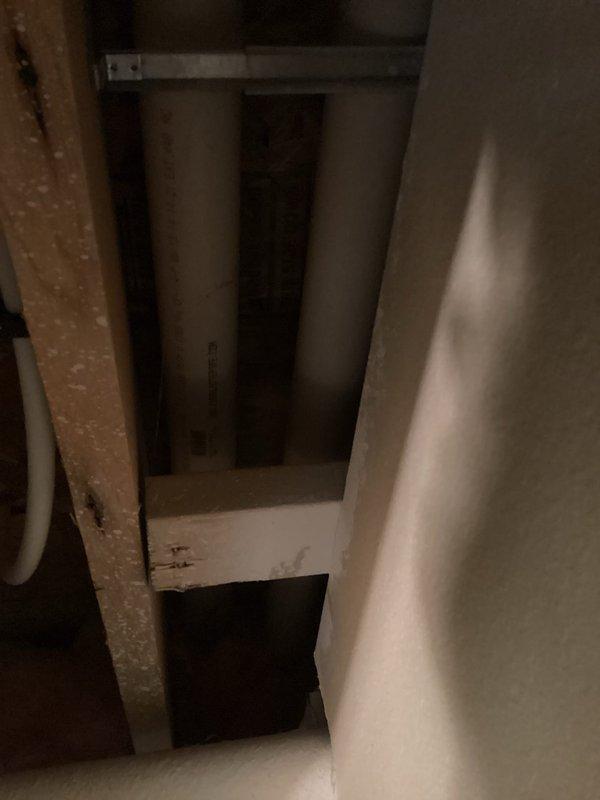 Responded to installation inspection violation regarding improper venting material. Upon arrival, located HVAC exhaust termination on exterior wall with cellcore piping used for combustion venting system. Inspected interior mechanical chase and confirmed non-compliant cellcore pipe installation running vertically through shaft. Documented existing conditions with photographs showing exterior termination point with beige oval vent cover mounted on vinyl siding and interior view of gray metal ducts within the vertical chase space. Corrected venting system by replacing cellcore piping with proper CPVC or approved venting material per manufacturer specifications and local code requirements to ensure safe exhaust of combustion gases and pass final inspection.