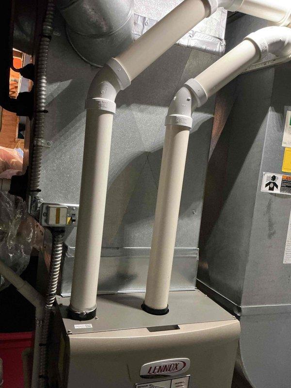 Responded to service call for Lennox furnace running excessively with inadequate heating and noise issues that began following recent AC service two days prior. Upon arrival, performed complete system diagnostic including visual inspection of indoor air handler unit, ductwork connections, and outdoor condensing unit. Verified PVC condensate drain lines and venting system were properly installed and functioning. Checked all electrical connections, conduit routing, and safety controls. Inspected blower motor operation, heat exchanger, and air flow through system. Documented equipment condition with photographs showing proper installation of vertical PVC piping from furnace, secure duct connections to metal plenum, and outdoor unit positioning on concrete pad. System producing some heat but not achieving adequate temperature rise across heat exchanger. No error codes present at time of inspection.