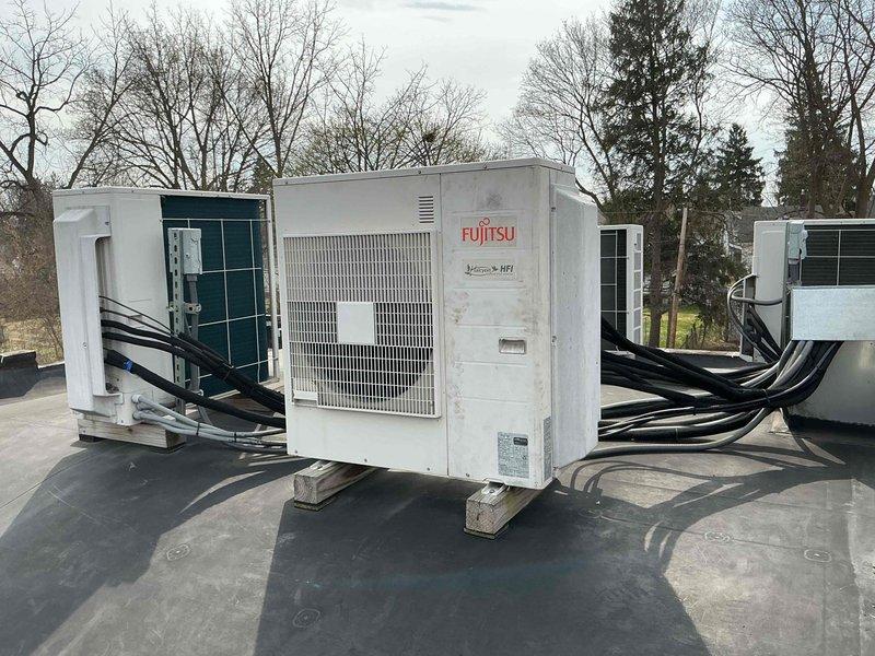 Completed diagnostic service on rooftop multi-zone Fujitsu heat pump system at vacant apartment unit. Accessed rooftop equipment with 8-foot ladder, counted diagnostic flash codes on indoor air handlers, and verified sensor operation per technical support guidance. Documented equipment condition and electrical connections serving multiple condensing units with photos for service records.