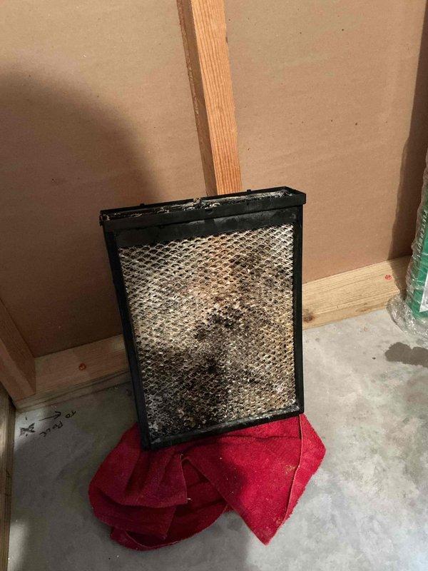 Responded to water leak concern near HVAC system. Upon arrival, inspected area where standing water was reported around equipment. Discovered heavily soiled air filter with significant debris accumulation that was restricting airflow and causing condensate drainage issues. Identified water heater in proximity to HVAC system with copper piping and shutoff valve. Documented conditions with photographs showing filter condition and equipment setup. Removed and displayed contaminated filter to show extent of blockage. Recommended filter replacement and verified condensate drain line functionality to prevent future water accumulation issues.