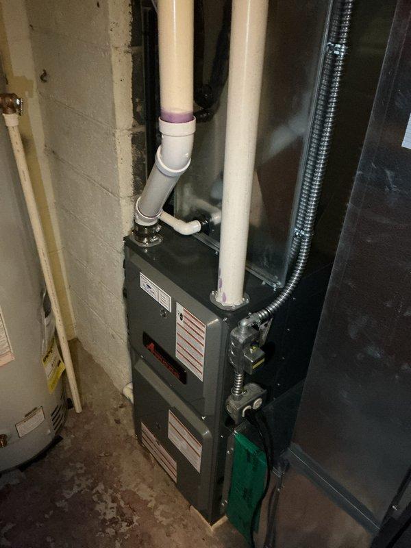 Responded to no cooling complaint at residential property. Upon arrival, contacted customer as requested prior to entry. Performed diagnostic inspection of air conditioning system with unknown age. Documented existing HVAC installation including furnace unit with PVC venting system and metallic ductwork in basement utility area. Inspected exterior condensing unit location at foundation level. Captured photographic documentation of equipment and installation for service records.