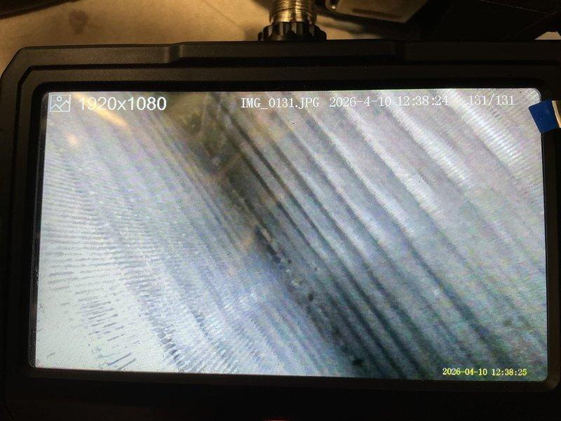 Installed heat shield for furnace to protect surrounding components from excessive heat exposure. Inspected heat exchanger fins using borescope camera, noting accumulated debris and discoloration on metallic surfaces. Verified system operation with multimeter readings showing 173.8V and temperature at 78.7°F, confirming proper electrical function and airflow after installation.