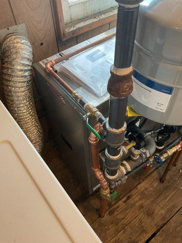 # HVAC Install - Boiler

Completed full boiler replacement in residential mechanical room. Removed existing boiler unit and mounted new boiler on stable, level surface with proper clearances. Connected supply and return piping to boiler using copper pipe with appropriate fittings, joints, and elbows. Installed required safety devices including pressure relief valve and water level gauge per manufacturer specifications and code requirements.

Connected gas line to main gas supply with secure, leak-free connections and installed gas shutoff valve for system safety. Performed complete electrical wiring per manufacturer's diagram and local electrical codes, connecting control panel, thermostats, and zone controls as required for proper system operation.

Installed white cylindrical expansion tank on metal frame with proper piping connections to accommodate system thermal expansion. Routed black vertical vent piping through ceiling for proper combustion exhaust. Integrated new boiler with e